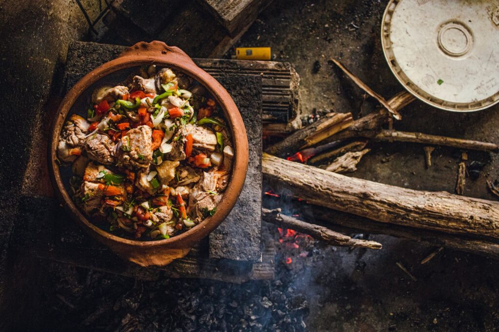 Un pot en terre rustique cuisinant de la viande et des légumes sur un feu de bois ouvert au Brésil, mettant en valeur la cuisine traditionnelle.