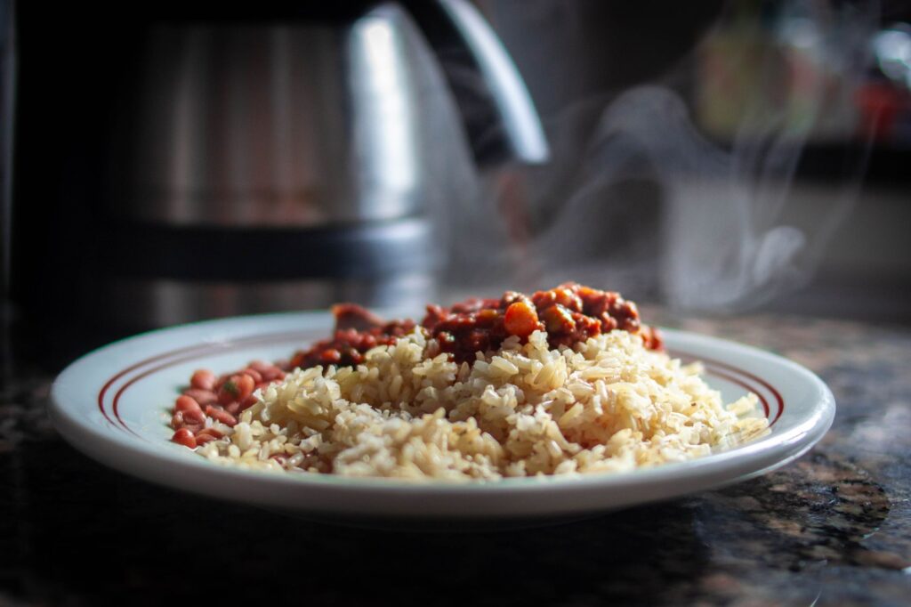 Gros plan de riz fumant avec des haricots chili sur une assiette, mettant en valeur la nourriture savoureuse.