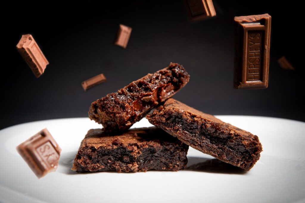Délicieux brownies au chocolat sur une assiette en céramique avec des barres de chocolat flottantes, parfaits pour les amateurs de desserts.