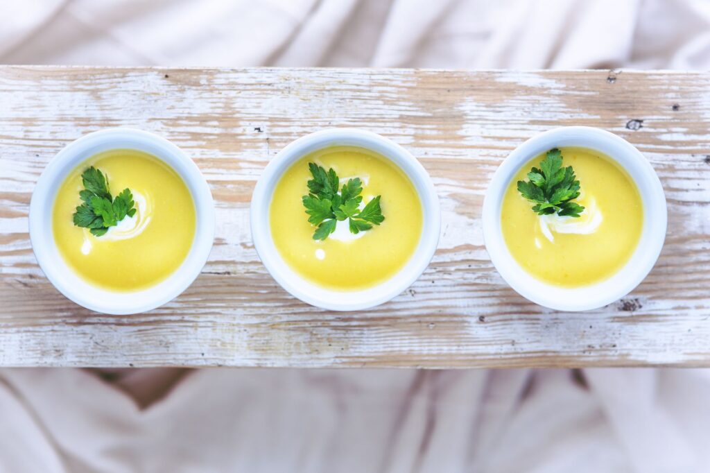Vue de dessus de trois bols de soupe de poireaux et pommes de terre vibrante garnie de persil frais.