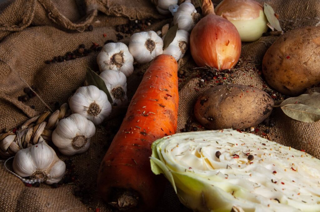 Une collection de légumes biologiques frais, y compris des carottes, de l'ail et des pommes de terre sur un fond en toile de jute.