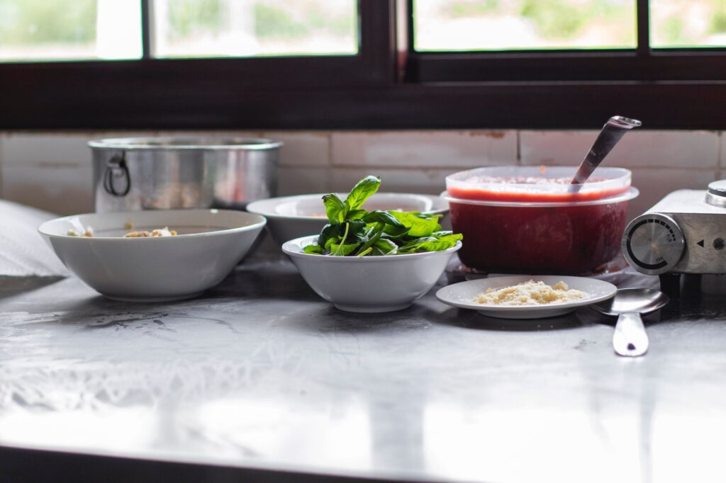 Scène de préparation avec du basilic frais, du parmesan et de la sauce tomate sur un plan de travail.