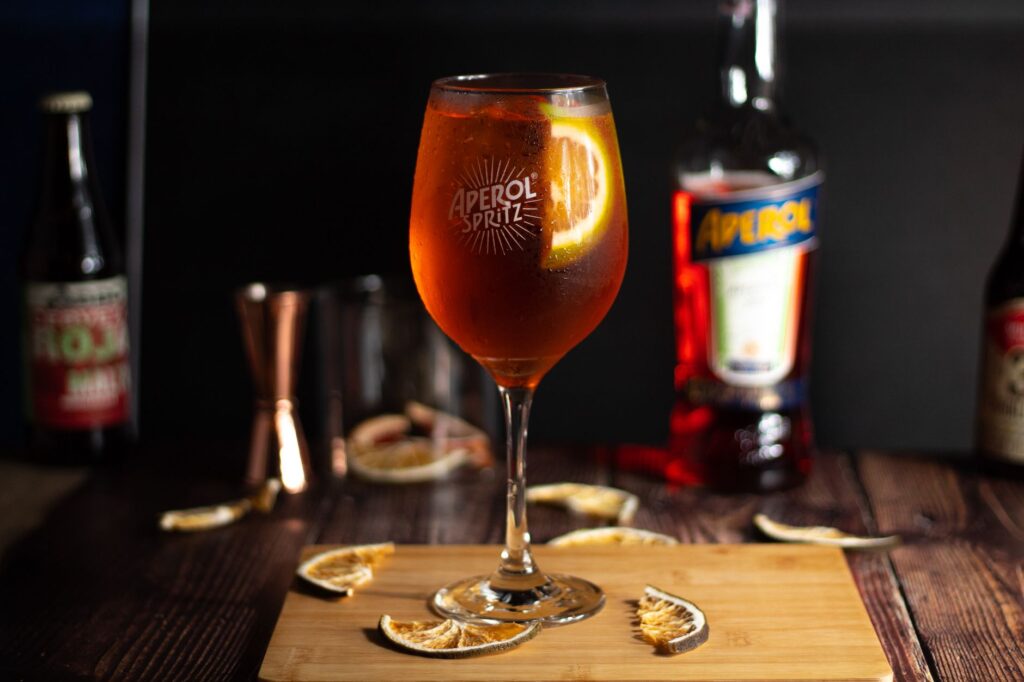 Gros plan sur un cocktail Aperol Spritz vibrant avec des tranches d'orange, parfait pour un apéritif d'été.