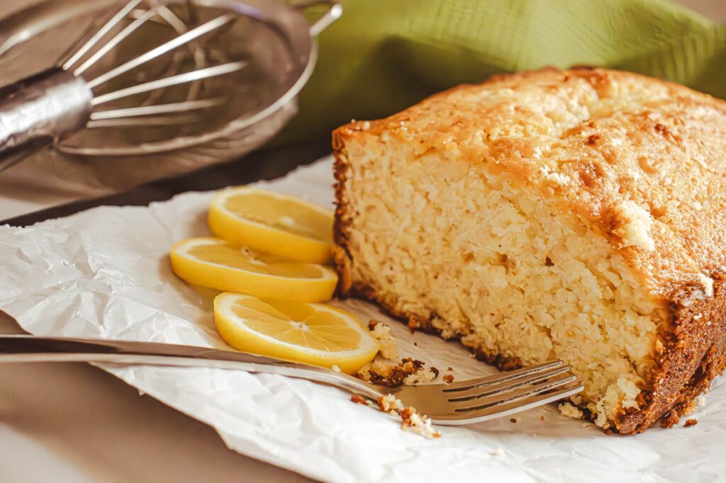 Gros plan d'un gâteau au citron sur du papier sulfurisé avec des tranches de citron frais, idéal pour la photographie culinaire.
