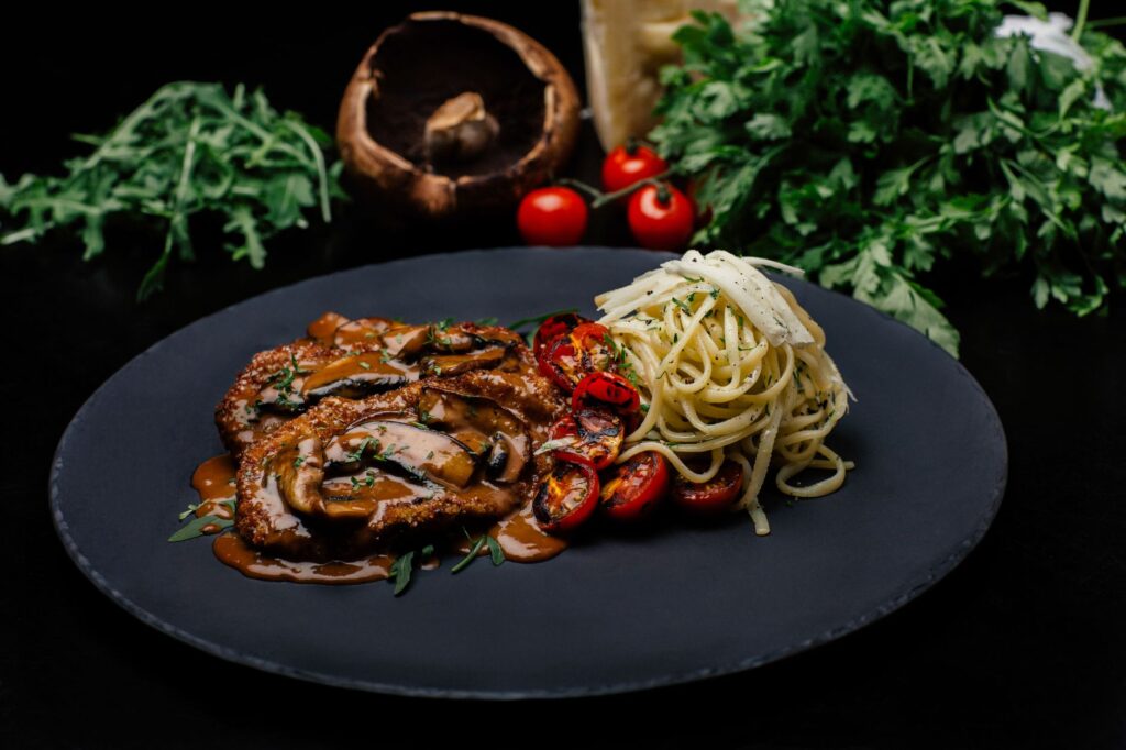 Délicieuses escalopes de veau avec sauce aux champignons et pâtes, garnies d'herbes fraîches.