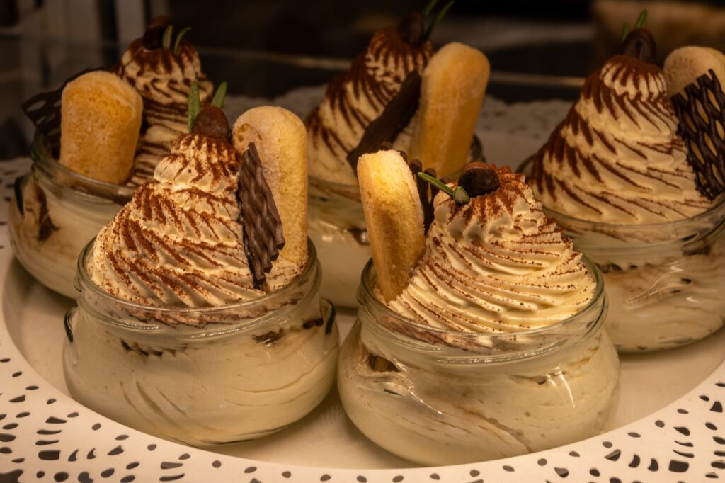 Délicieux tiramisu servi dans des bocaux en verre élégants, garni de chocolat et de biscuits à la cuillère.