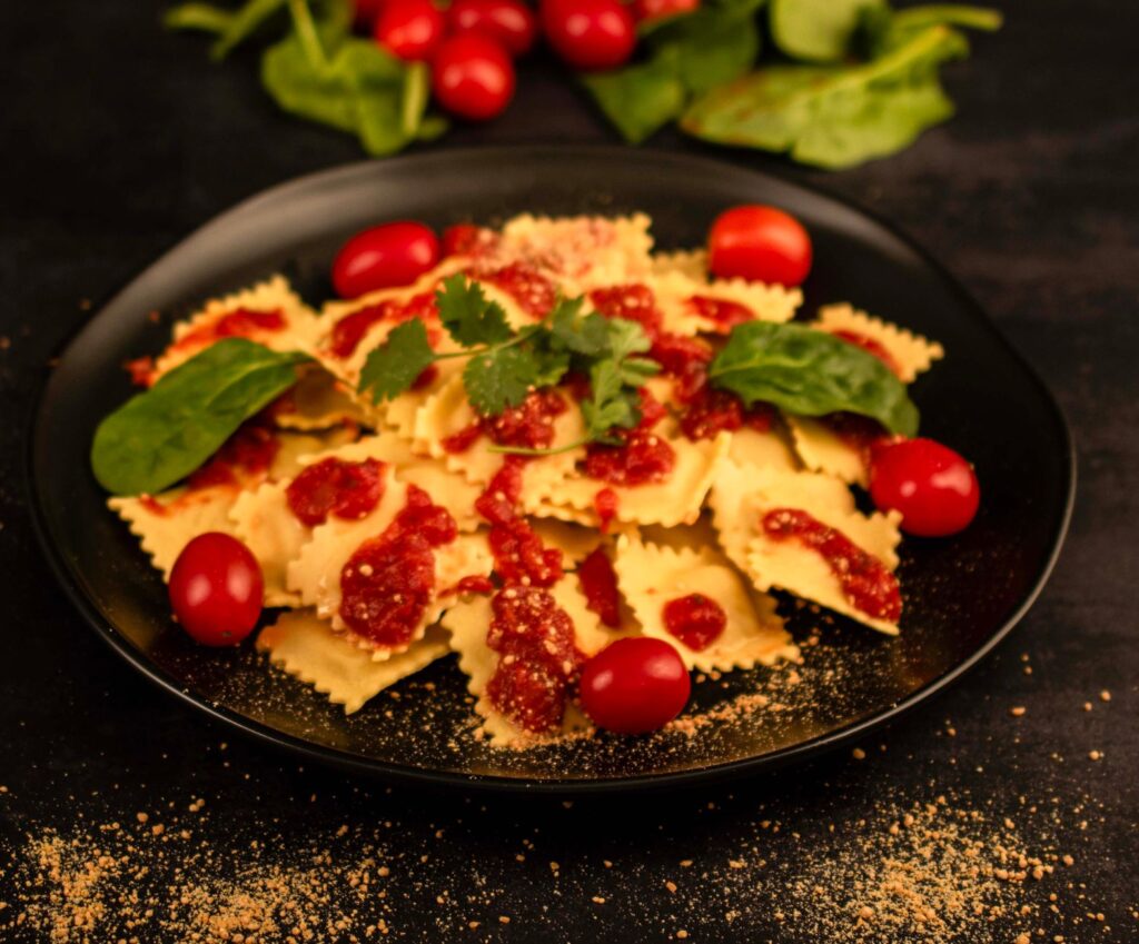 Assiette appétissante de ravioli garnie de sauce tomate, de basilic frais et de tomates cerises.