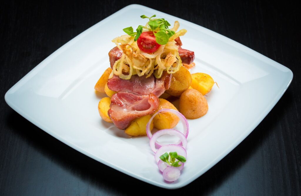 Plat gourmet avec bacon, pommes de terre et oignons sur une assiette blanche. Parfait pour le contenu culinaire.