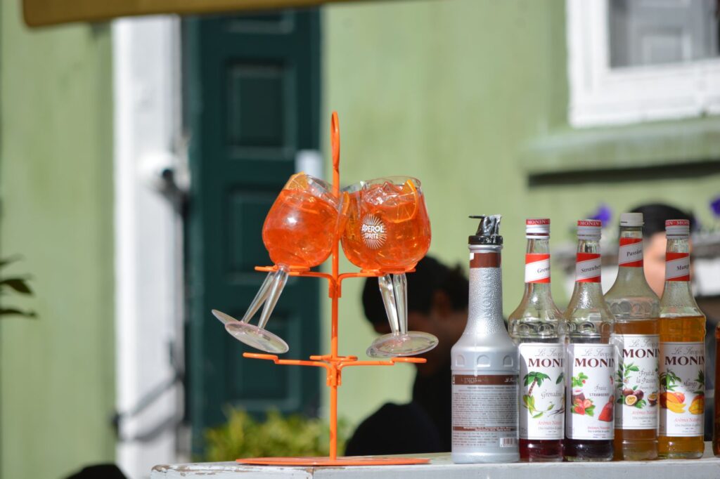 Aperol Spritz coloré et sirops Monin exposés à l'extérieur, parfaits pour des cocktails d'été.