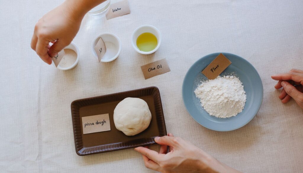 Vue de dessus des ingrédients essentiels pour préparer une pâte à pizza italienne, y compris l'huile d'olive, la farine et la levure.