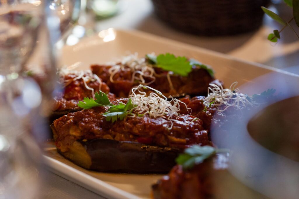 Gros plan d'aubergine farcie, garnie de sauce tomate et décorée d'herbes.