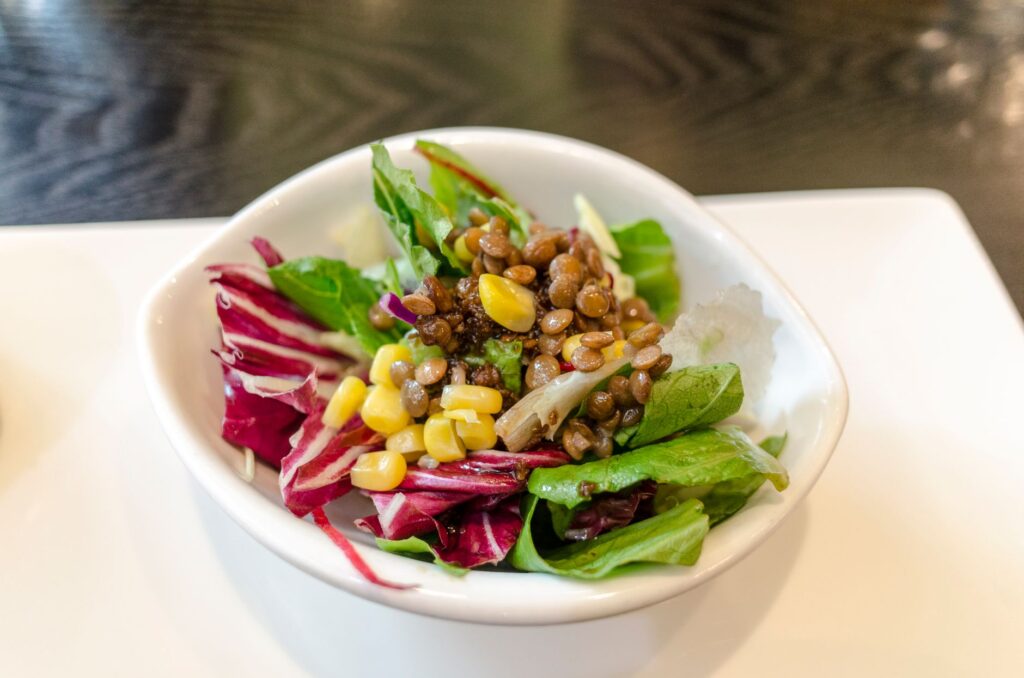 Une salade de légumes fraîche et délicieuse comprenant des lentilles et du maïs servie dans un bol blanc.