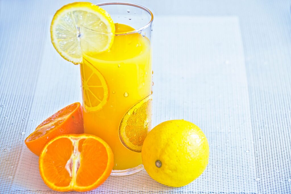 Jus d'agrumes vibrant dans un verre avec des tranches d'orange et de citron fraîches, offrant un goût rafraîchissant d'été.