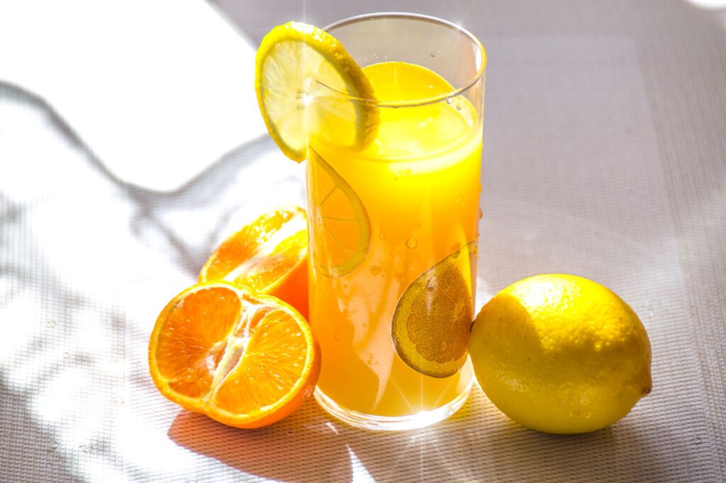 Jus d'agrumes lumineux et rafraîchissant dans un verre avec des tranches de citron et d'orange fraîches.